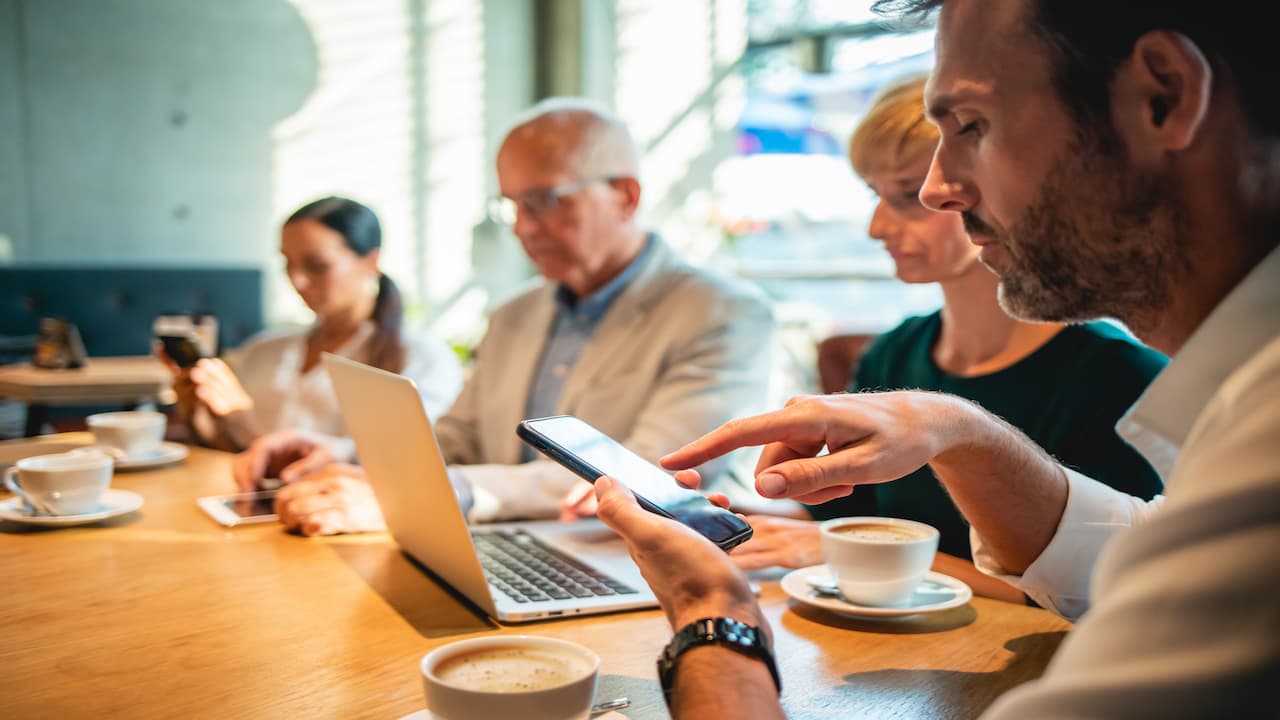 Un gruppo di persone al bar con il proprio device per indicare cosa facciamo di più quando siamo online